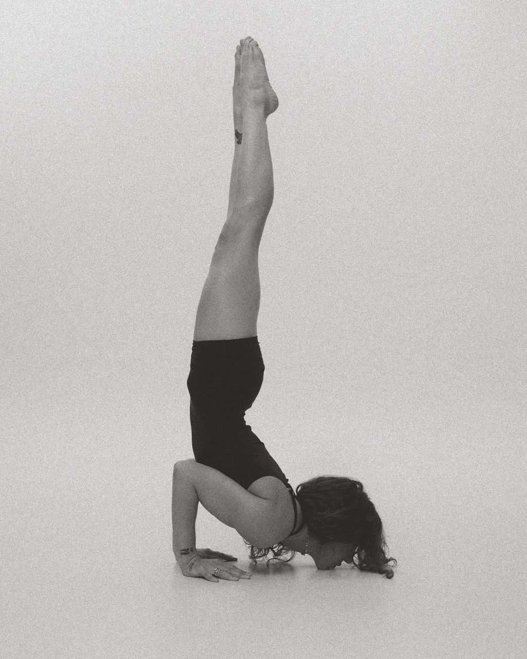 A headstand (sirsasana) against a light background