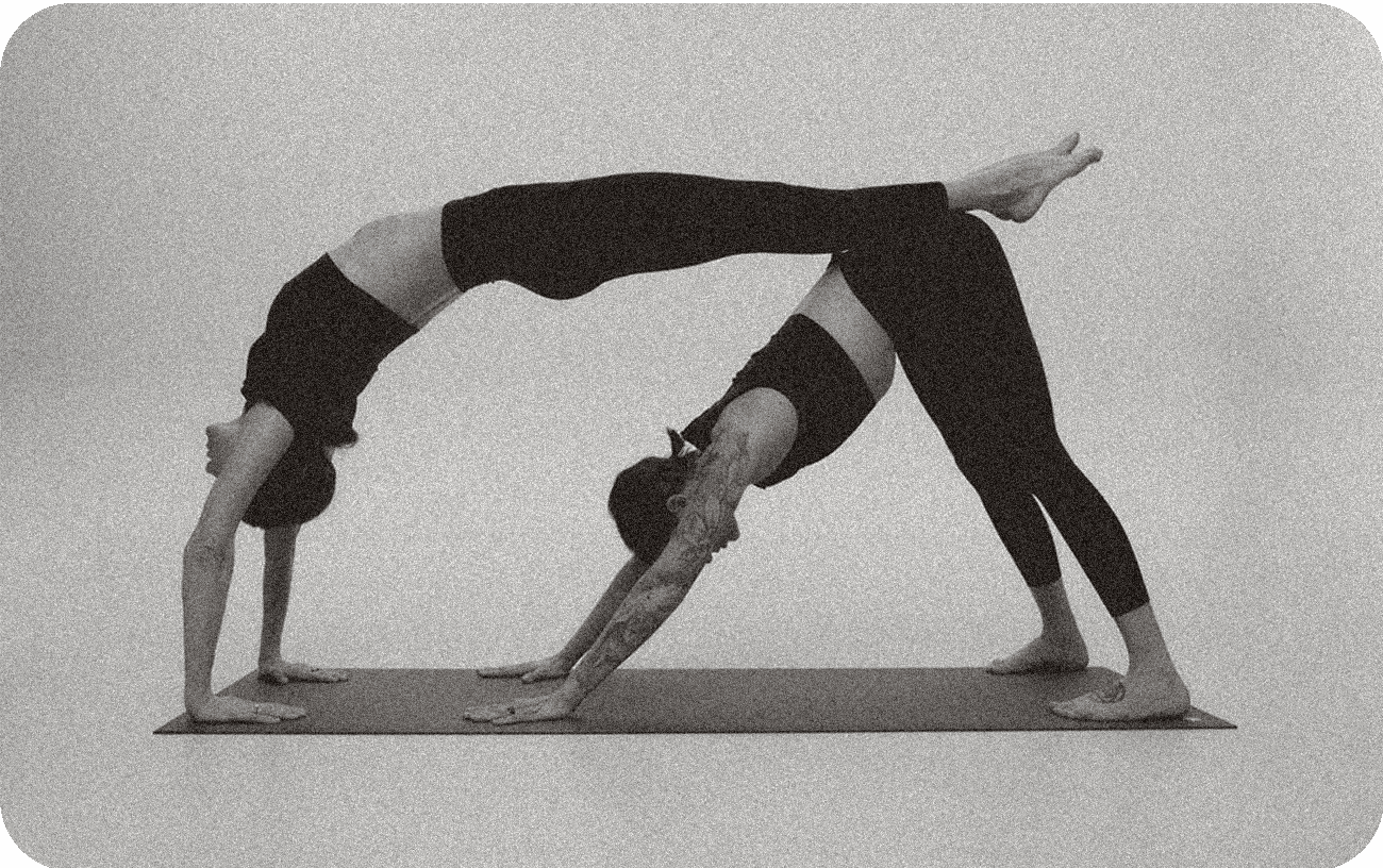 Two people practising a partner pose on a mat at 108 in-se